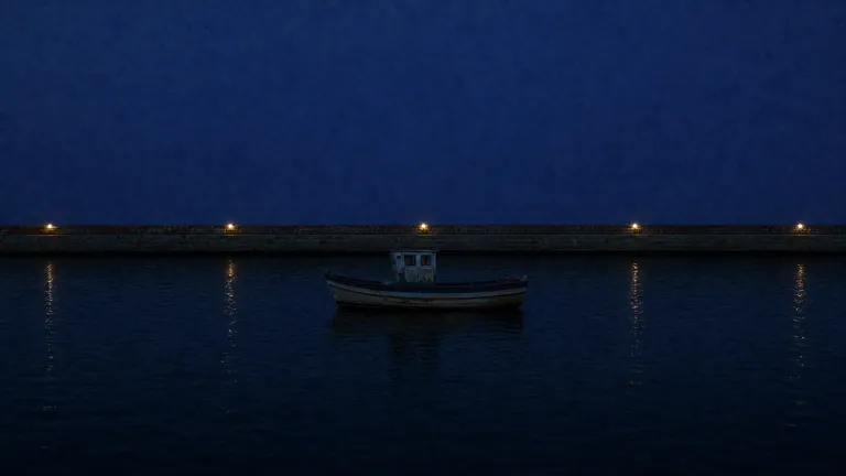 A dark harbour at night with a small boat